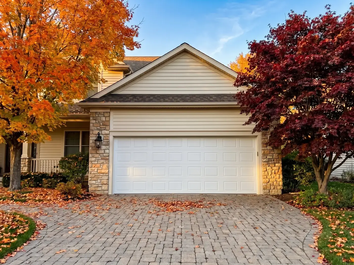 White garage door on a stone-front home in autumn